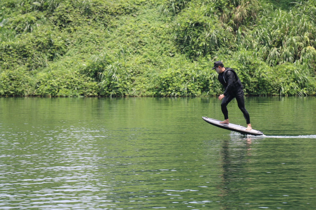 An electric hydrofoil enthusiast riding an eFoil smoothly on a calm lake