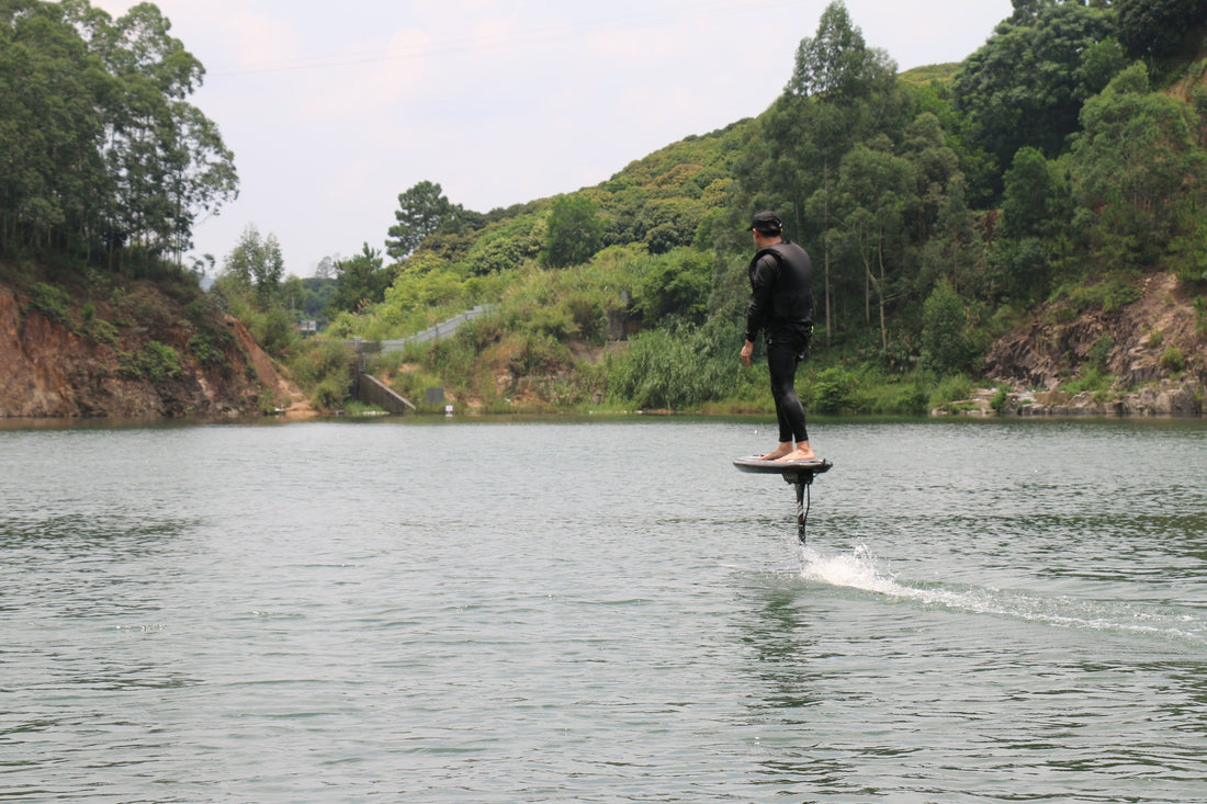A rider standing on an electric hydrofoil, practising calmly on a glassy, wave-free water surface.
