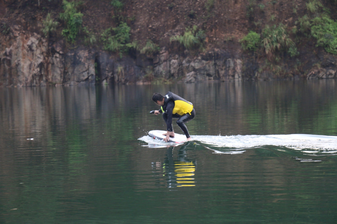 A person practicing electric hydrofoiling on calm water, focusing on balance and smooth control.
