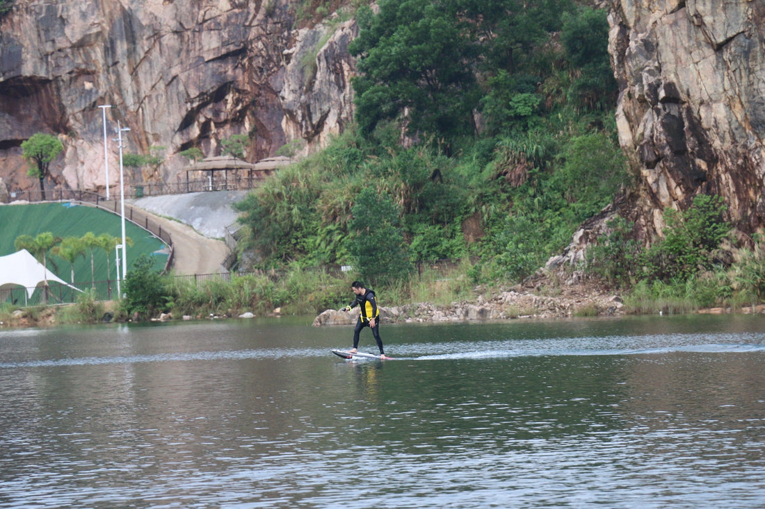 A person struggling to stay on an electric hydrofoil, tipping toward the water.
