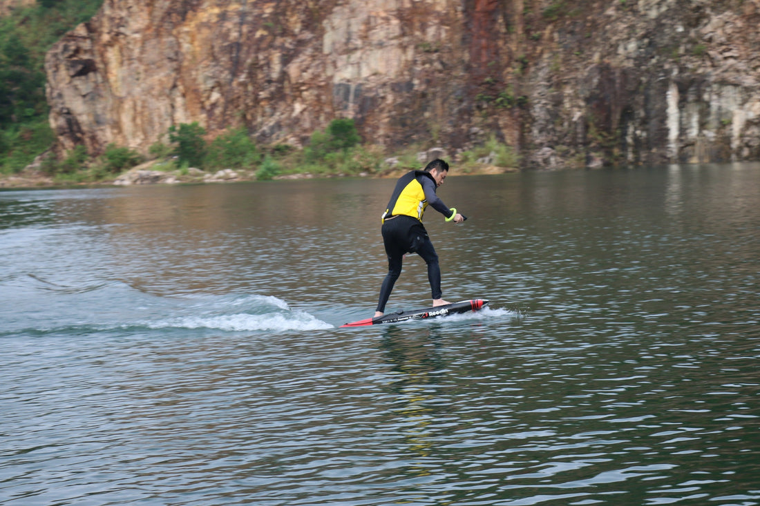 A rider on an e-foil teetering, moments away from falling into the water.