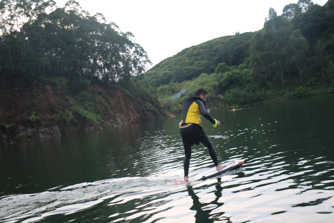 An electric hydrofoil beginner practicing on a calm lake, learning balance and control