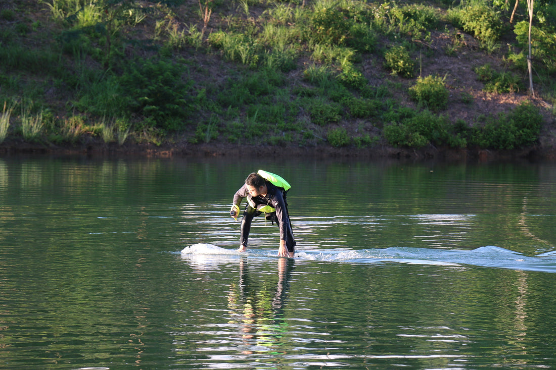 A person practicing on an electric hydrofoil board over calm, still water.