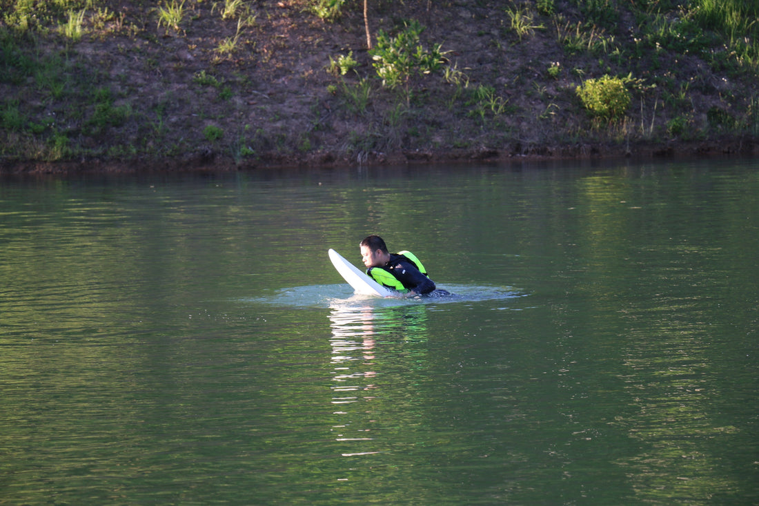 An electric hydrofoil beginner practicing on a calm lake, learning balance and control